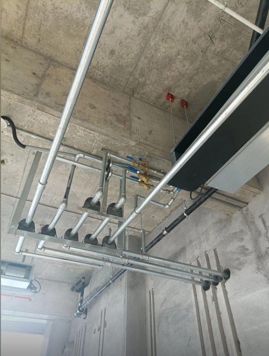 Commercial ceiling fan coil unit installation with exposed piping