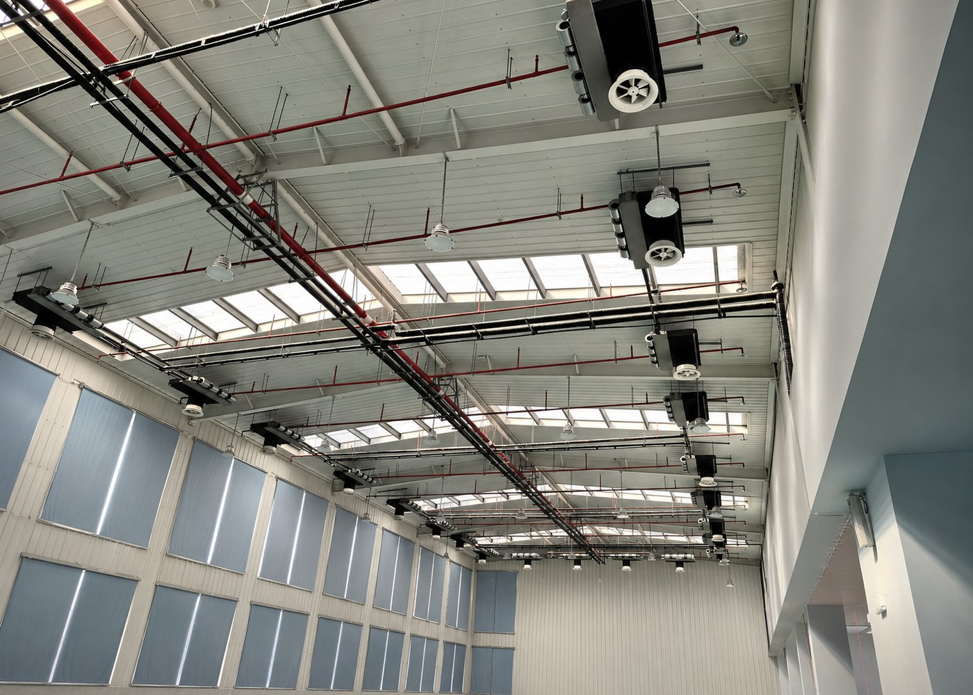 Commercial hall ceiling with multiple horizontal fan coil units and exposed service piping